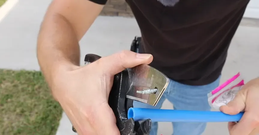 Plumber cutting blue PEX water supply pipe with a pipe cutter