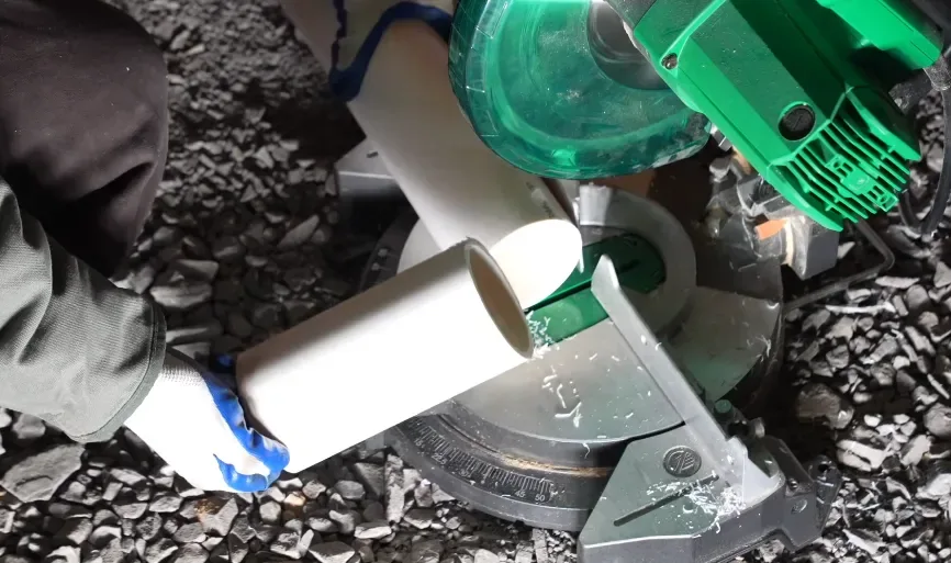 Plumber cutting PVC sewer pipe to length with a power saw