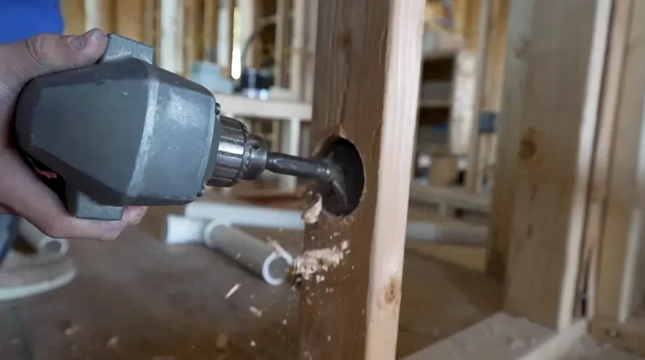 Drilling a hole through a wall stud to route new water pipe